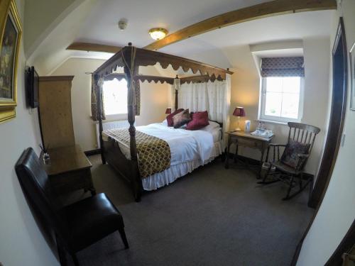 Horsted KeynesThe Crown Inn的一间卧室配有一张天蓬床和一张桌子及椅子