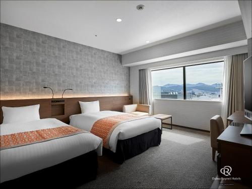 广岛Daiwa Roynet Hotel Hiroshima-ekimae的酒店客房设有两张床和窗户。
