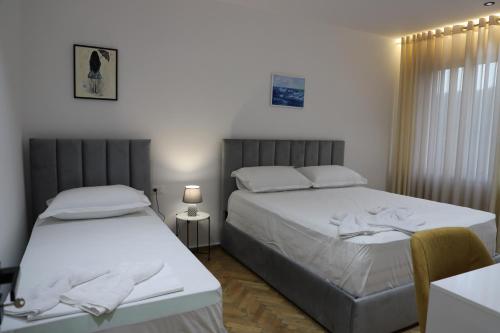 培拉特Noel City Centre Apartment的一间卧室配有两张床和一张带台灯的桌子