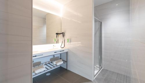 里斯本AMMA Lisboa Hotel的白色的浴室设有水槽和淋浴。