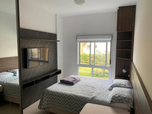 弗洛里亚诺波利斯Apartamento na Praia do Campeche的一间卧室配有镜子、一张床和一个窗户