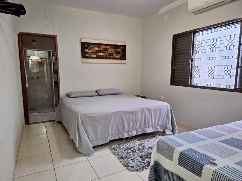 乌贝拉巴Casa de temporada Uberaba piscina的一间卧室设有一张床、一个窗口和淋浴