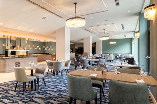 霍利希尔顿伦敦盖特威克机场酒店的一间带桌椅的餐厅和一间酒吧