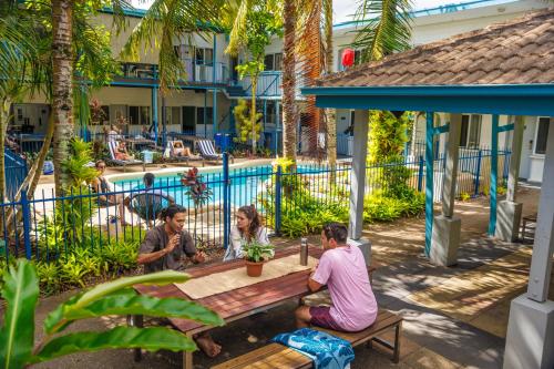 凯恩斯YHA Cairns Central的一群坐在泳池旁野餐桌上的人