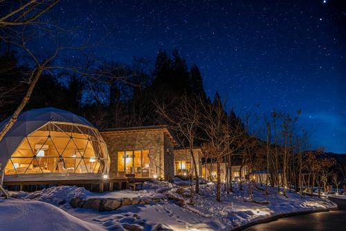 阿智村mokki STARDUST GLAMPING的夜晚雪中的一个玻璃屋