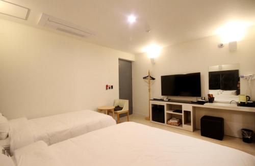 釜山Bandal Hotel的酒店客房设有两张床和一台平面电视。