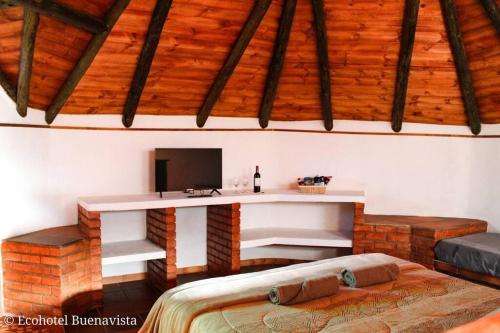 莱瓦镇Ecohotel Buenavista的客房设有一张桌子、一台电视和一张床