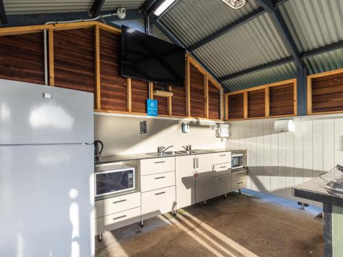坎贝尔港坎贝尔港恩阿马假日公园的厨房配有白色冰箱和木制橱柜。