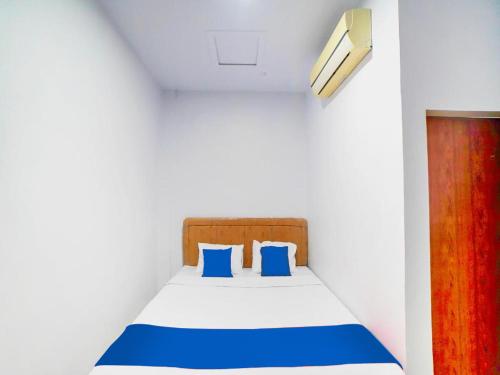 棉兰Sg Premium Guest House By Helocus的白色客房内的一张带蓝色枕头的床