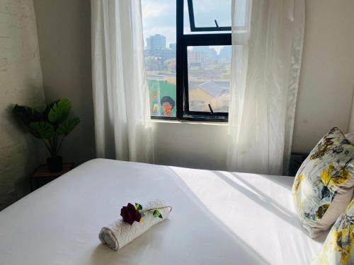 约翰内斯堡Views from The 509的一张白色的床,上面有毛巾,还有窗户