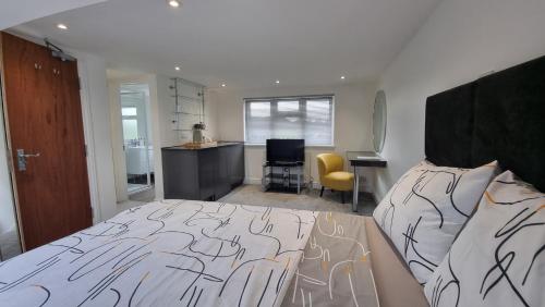 伦敦科尔尼Stylish Suites with kitchenette的一间带一张床和一张书桌的卧室和一间厨房