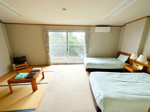 京丹后市森林公園スイス村 風のがっこう京都的客房设有两张床、一张桌子和一扇窗户。
