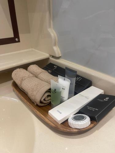 尼兹瓦Nizwa Park House Apartment的浴室柜台上备有毛巾和化妆品的托盘
