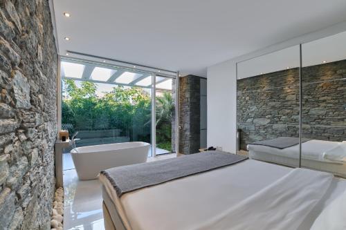 普洛马里翁A - Luxury Villas的一间卧室设有一张大床、一个浴缸和石墙