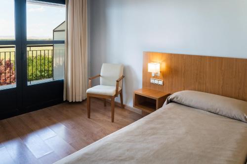 蒙雷阿尔-德尔坎波阿斯蒙雷亚尔坎波酒店的卧室配有床、椅子和窗户。