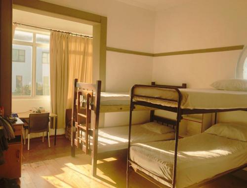 开普敦Ben Your Friend Youth Foundation的一间卧室设有两张双层床、一张桌子和一扇窗户。
