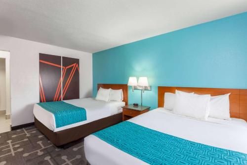 纳欣诺市霍华德约翰逊快捷汽车旅馆的两张位于酒店客房的床,拥有蓝色的墙壁