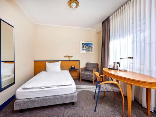杜塞尔多夫杜塞尔多夫市中心美居酒店的配有一张床和一张书桌的酒店客房