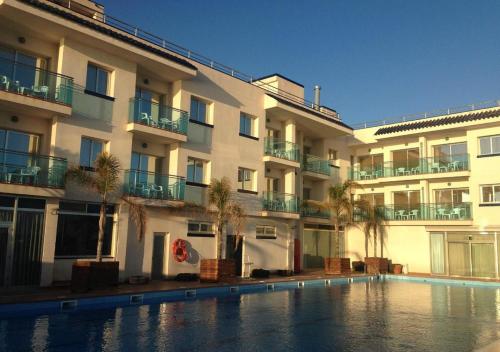 锡切斯锡切斯港酒店的大楼前设有游泳池的酒店