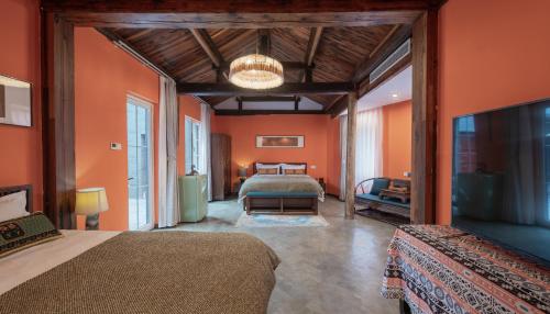 北京壹·色四合院酒店的一间卧室设有橙色墙壁、两张床和电视。