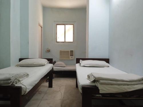 加尔各答Centerpoint Guest House的带窗户的客房内设有两张单人床。
