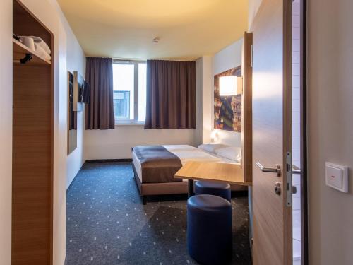 拜罗伊特B&B Hotel Bayreuth的配有一张床和一张书桌的酒店客房