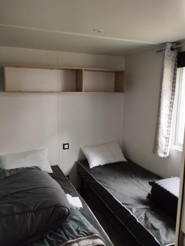 滨海皮里亚克MOBIL HOME的一间卧室设有两张床和窗户。