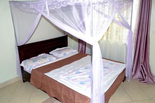 Njeruolive Palm Suites的一间卧室配有一张带紫色窗帘的天蓬床