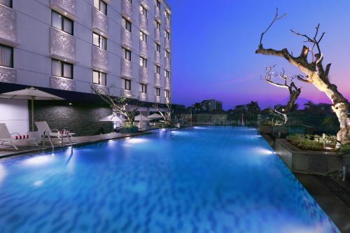 日惹Hotel Neo Malioboro by ASTON的夜间在酒店前的游泳池