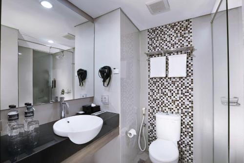 日惹Hotel Neo Malioboro by ASTON的白色的浴室设有水槽和卫生间。