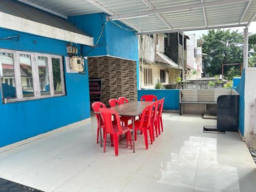 达曼Chirag Banglow 2BHK的庭院里设有一张木桌和红色椅子