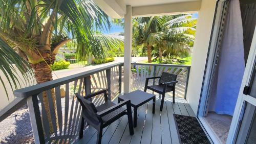 拉罗汤加Studio Varia的阳台配有两把椅子和一张桌子,还种植了棕榈树