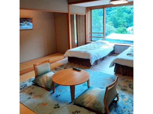 雫石町Oshuku Onsen Choeikan - Vacation STAY 55588v的一间设有两张床和一张桌子及椅子的房间