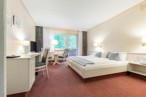 巴德贝芬森Hotel Ilmenautal inklusive THERMEplus的配有一张床和一张书桌的酒店客房