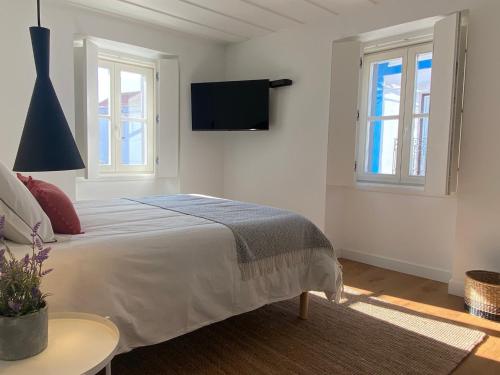 格兰杜拉Grândola Suites - Suite Afonso的白色卧室设有一张床和墙上的电视