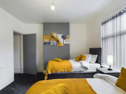 特伦特河畔斯托克Cliff House By RMR Accommodations - NEW - Sleeps 8 - Modern - Parking的一间卧室设有两张床和黄色毯子
