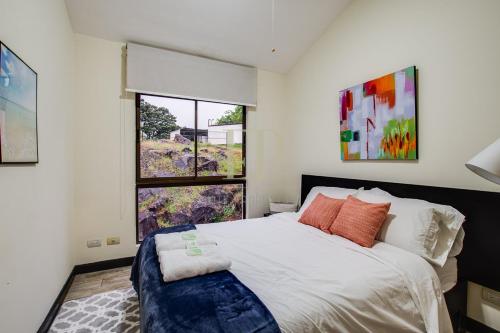 圣安娜CR MARIPOSA RENTALS Comfortable penthouse, AC, pool, gym, tennis的一间卧室设有一张大床和一个窗户。