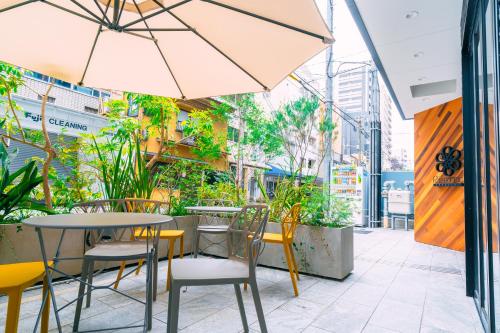 大阪R Hotel Honmachi的户外休息区配有桌椅和遮阳伞。