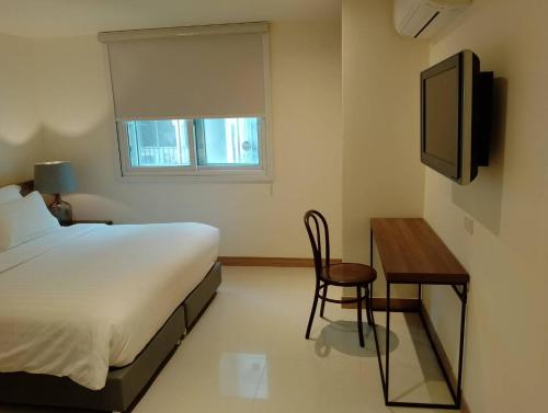 芭堤雅市中心芭堤雅西山酒店的一间卧室配有一张床、一张书桌和一台电视