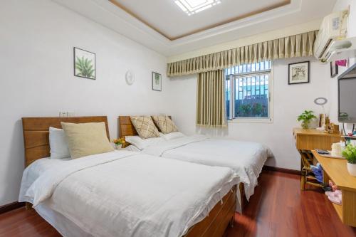 杭州西湖雷峰塔河坊街地铁口民宿的一间卧室设有两张床、一张桌子和一个窗口。
