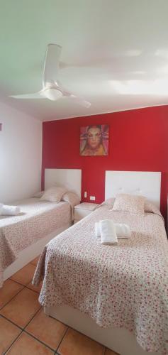 蒂亚斯Apartamentos JANESKA的一间卧室设有两张床和红色的墙壁