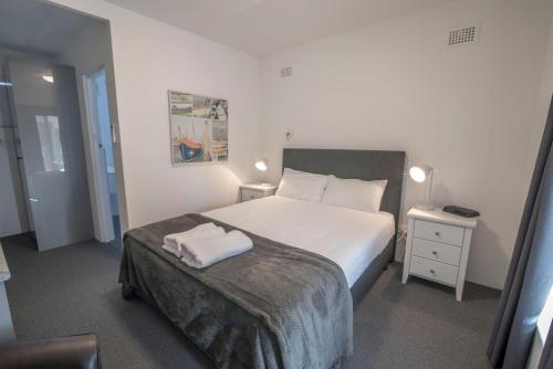 伯马吉柏马吉汽车旅馆的卧室配有一张白色的大床和床头柜。