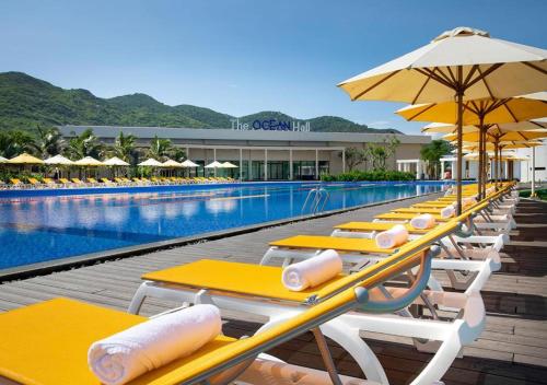 隆海Lovely Lady Villa Oceanami Resort, Vung Tau的游泳池旁一排带遮阳伞的桌子