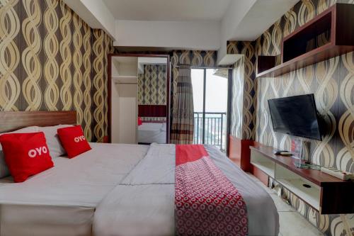 万隆OYO Life 92910 Apartemen Tamansari Panoramic By Tira的一间卧室配有一张带红色枕头的床和一台电视。