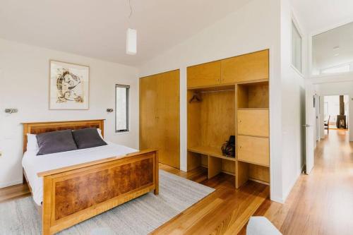 科尔斯湾Parsons Cove Beach House的一间卧室配有一张大床和木制橱柜。