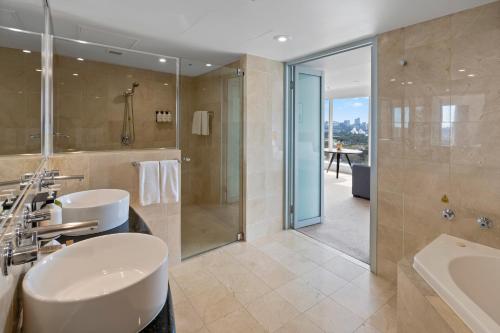 悉尼Holiday Inn Sydney Potts Point的浴室配有水槽、淋浴和浴缸。