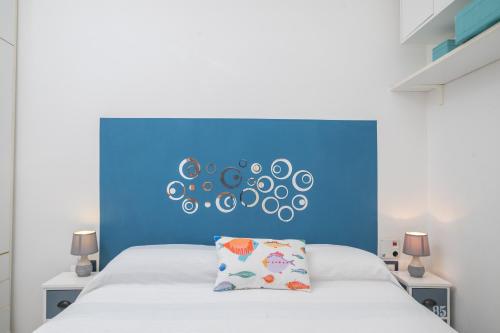 马里纳·迪·波迪斯科Sardinia Paradise House - Happy Rentals的一间卧室配有蓝色床头板和白色的床