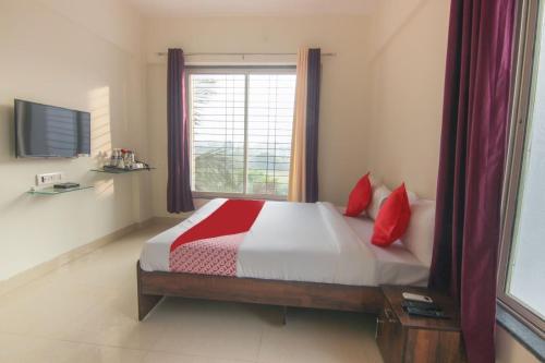 浦那Hotel Felicita Airport Inn的一间卧室配有一张带红色枕头的床和一扇窗户