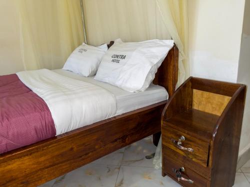 金贾Contra Hotel的一张带两个白色枕头和木桌的床
