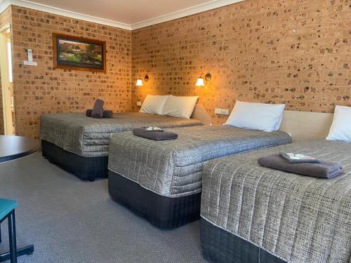 AberdeenAberdeen Motel的酒店客房,设有三张床和砖墙